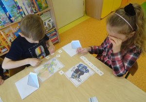 Dzieci układają przy stoliku obrazki z części oraz rozsypanki literowe.